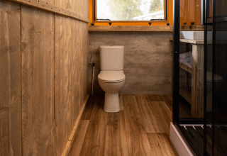 Baño con paredes de madera y inodoro en la tienda Safari 'the bartender' en Holiday Park Mölke, Países Bajos.