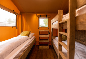 Interieur van safaritent 'the bartender' met eenpersoonsbed en stapelbed, Holiday Park Mölke, Nederland.