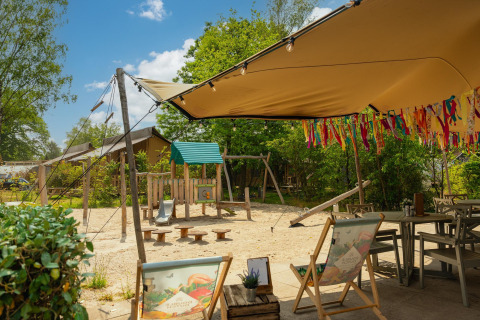 Área de juegos y asientos al aire libre junto a la tienda Safari 'the bartender' en Holiday Park Mölke, Países Bajos.