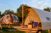 En Panorama Lodge med badeværelse i Holiday Park Mölke, Holland, med en mand der læser udenfor på terrassen.
