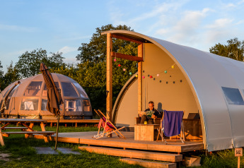 Panorama Lodge avec salle de bains au Holiday Park Mölke, Pays-Bas, homme lisant sur la terrasse au soleil.
