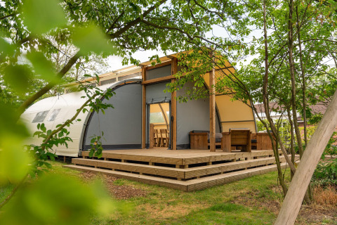 Panorama Lodge mit Bad im Holiday Park Mölke in den Niederlanden, umgeben von grünen Bäumen.