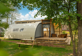 Buitenaanzicht van de Panorama Lodge met badkamer in Holiday Park Mölke, Nederland, omgeven door bomen.