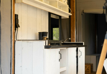 Pequeña cocina moderna con armarios blancos de madera en Panorama Lodge de Holiday Park Mölke, Países Bajos.