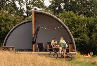 Family relaxing outside Panorama Lodge with bathroom at Holiday Park Mölke, Netherlands, on a summer day