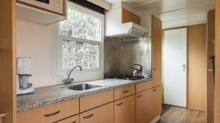 Moderne keuken in Bungalow at the Regge met fornuis, koffiezet en raam, Holiday Park Mölke, Nederland.