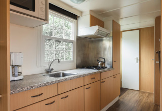 Moderne keuken in Bungalow at the Regge met fornuis, koffiezet en raam, Holiday Park Mölke, Nederland.