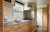 Modern kitchen in the Bungalow at the Regge with stove, coffee maker and window at Holiday Park Mölke, Netherlands.