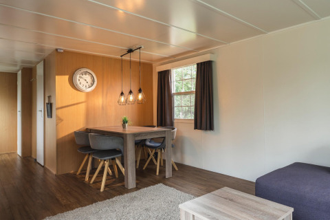Moderne woon- en eetkamer in Bungalow aan de Regge, Holiday Park Mölke, Nederland, met houten meubels.