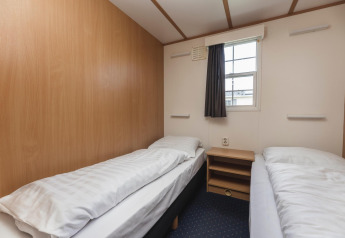 Two single beds in a simple, bright room at Bungalow at the Regge in Holiday Park Mölke, Netherlands.