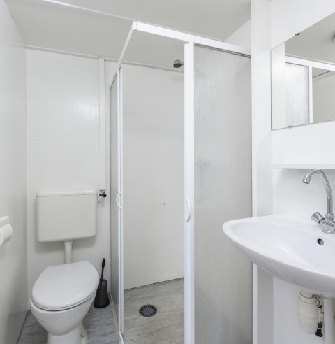 Baño con ducha, inodoro y lavabo en un bungalow junto al Regge en Holiday Park Mölke, Países Bajos.