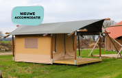 Safari-Zelt mit Holzrahmen auf einer Wiese, Schild mit 'NIEUWE ACCOMMODATIE' in blauer Sprechblase.