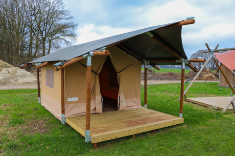 Safaritent met houten structuur en veranda bij Holiday Park Mölke in Nederland, midden in het groen.