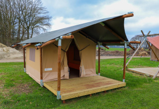 Safaritent met houten frame en veranda op Holiday Park Mölke in Nederland, gelegen op een grasveld.