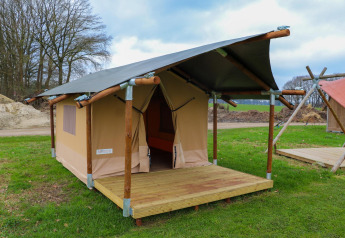 Safaritent met houten structuur en veranda bij Holiday Park Mölke in Nederland, midden in het groen.