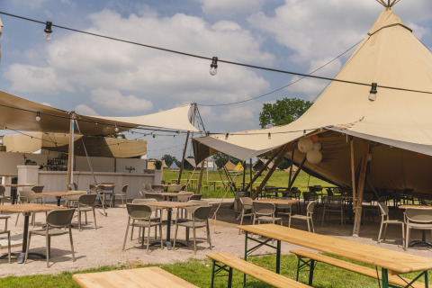 Buiten zitplaatsen onder safaritenten bij Pop-up glamping Neighbor's Awaji in Holiday Park Mölke, Nederland.