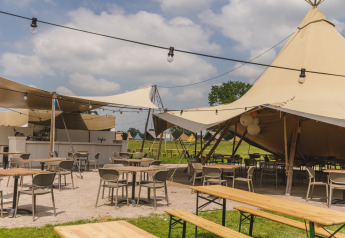 Buiten zitplaatsen onder safaritenten bij Pop-up glamping Neighbor's Awaji in Holiday Park Mölke, Nederland.