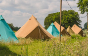 Row of colorful teepee tents at Pop-up glamping: Belltent, Holiday Park Mölke, Netherlands, surrounded by grass.