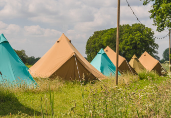 Reihe von bunten Tipi-Zelten im Holiday Park Mölke in den Niederlanden, umgeben von Gras und Bäumen.