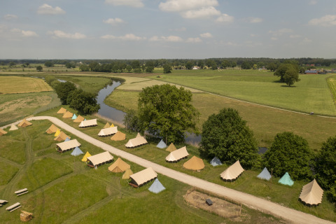 Vista aérea de tiendas belltent en el Pop-up glamping Holiday Park Mölke, rodeadas de campos y río en Países Bajos.