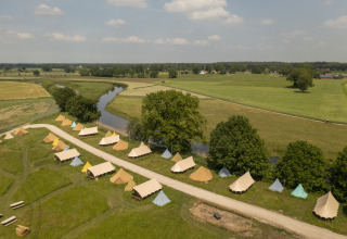 Aerial view of bell tents at Pop-up glamping, Holiday Park Mölke, Netherlands, with fields and a river nearby.