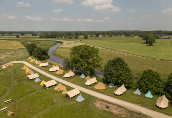 Luchtbeeld van belltenten bij Pop-up glamping bij Holiday Park Mölke, omgeven door velden en rivier in Nederland.