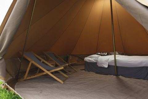 Interior de una tienda tipi acogedora con sillas y cama en Pop-up glamping: Belltent en Holiday Park Mölke, Países Bajos.