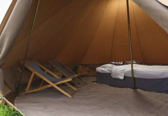 Interno di una tenda tipi accogliente con sedie e letto presso Pop-up glamping: Belltent, Holiday Park Mölke, Olanda.