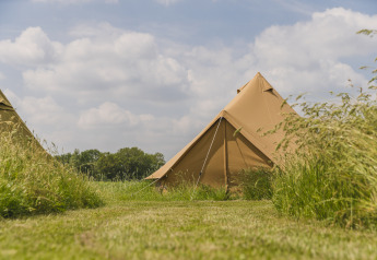 Tipitent op een grasveld onder blauwe lucht, Pop-up glamping: Belltent bij Holiday Park Mölke, Nederland.