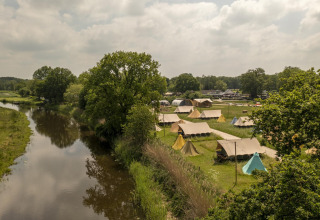 Luftaufnahme von Pop-up Glamping Awaji-Zelten im Holiday Park Mölke, neben einem Fluss in den Niederlanden.