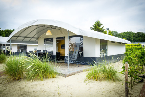 Safari tent Tent Villa at Holiday Park Duinhoeve in the Netherlands with covered outdoor seating area.