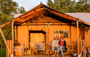 To personer slapper af foran et luksus glamping-telt i Holiday Park Mölke, Holland, omgivet af natur.
