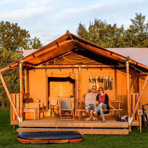 Dos personas sentadas frente a una tienda glamping de lujo en Holiday Park Mölke en los Países Bajos.