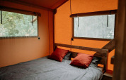 Zona notte con letto matrimoniale e cuscini rossi in una lussuosa tenda glamping presso Holiday Park Mölke, Paesi Bassi.