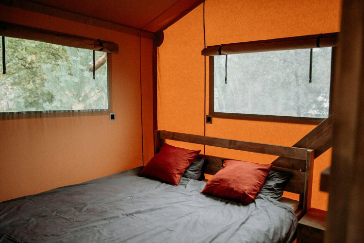 Área de dormitorio con cama doble y cojines rojos en lujosa tienda glamping en Holiday Park Mölke, Países Bajos.