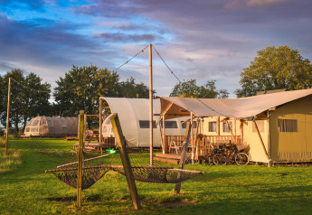 Luxuriöse Glamping-Zelte im Holiday Park Mölke in den Niederlanden bei Sonnenuntergang und Wiese.