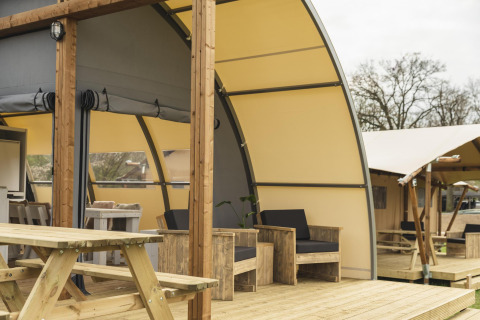 Udendørs opholdsområde ved luksus glamping-telt på Holiday Park Mölke i Holland med træmøbler.