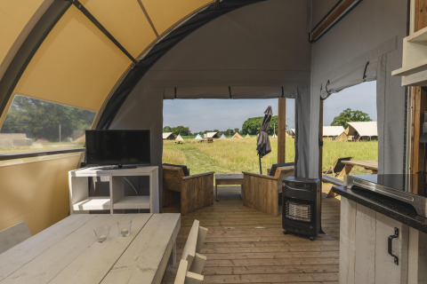 Intérieur d'une tente de glamping de luxe au Holiday Park Mölke, Pays-Bas, avec coin salon et télévision.
