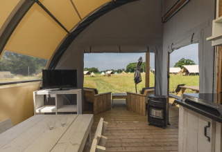 Intérieur d'une tente de glamping de luxe au Holiday Park Mölke, Pays-Bas, avec coin salon et télévision.