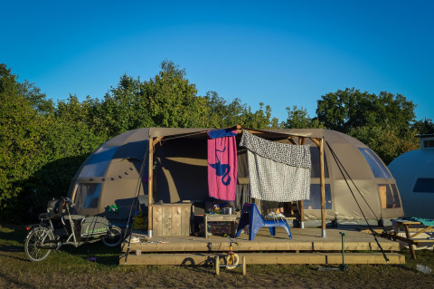 Tienda glamping de lujo en Holiday Park Mölke, Países Bajos, con bicicleta y ropa colgada afuera.