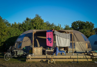 Tienda glamping de lujo en Holiday Park Mölke, Países Bajos, con bicicleta y ropa colgada afuera.