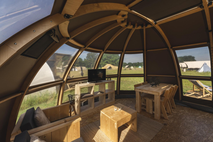 Interior de una lujosa tienda glamping en Holiday Park Mölke, Países Bajos, con muebles de madera y vista externa.