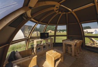 Intérieur d'une tente de glamping de luxe au Holiday Park Mölke, Pays-Bas, avec meubles en bois et vue extérieure.
