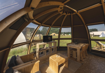Intérieur d'une tente de glamping de luxe au Holiday Park Mölke, Pays-Bas, avec meubles en bois et vue extérieure.