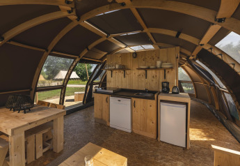 Interior de tienda glamping de lujo en Holiday Park Mölke, Países Bajos, con cocina y muebles de madera.