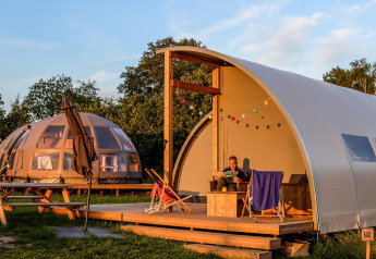 Tiendas de glamping de lujo en Holiday Park Mölke, Países Bajos, con terraza de madera y luces de colores.