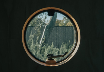 Finestra rotonda in una tiny house Wikkel a De Klepperstee, Paesi Bassi, che guarda verso il giardino.