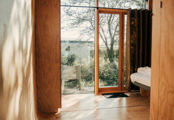 Intérieur de la tiny house Wikkel au Holiday park De Klepperstee, avec panneaux bois et vitrages lumineux.