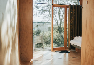 Binnenaanzicht van Wikkel tiny house op Holiday park De Klepperstee met houten wanden en groot raam.
