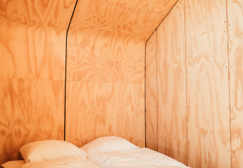 Minimalistisk træinteriør med dobbeltseng i Wikkel tiny house, Holiday park De Klepperstee, Holland.